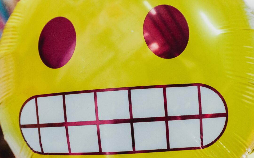 Close-up of a balloon shaped like the awkward smile emoji